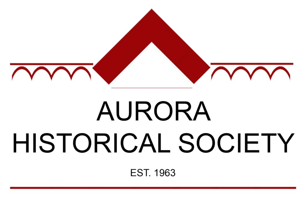 Aurora Historical Society Logo - Black title with EST. 1963 underneath, sits inside a minimalist outline of a red gothic roof and bargeboard.